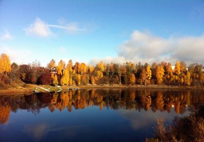 Reflection of autumn trees on calm lake against sky