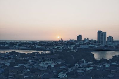 Aerial view of buildings in city against clear sky during sunset