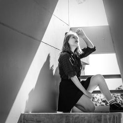 Young woman looking down while sitting against wall