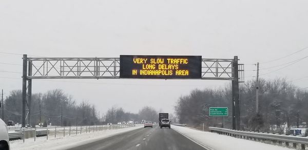 Road sign against sky during winter