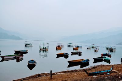 Boats moored on sea against clear sky