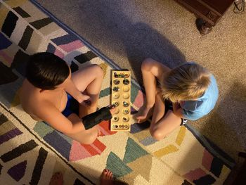 High angle view of siblings playing on floor