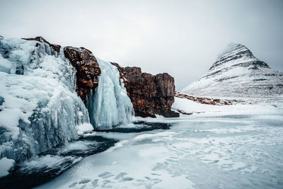 Scenic view of rock formations and glaciers against cloudy sky