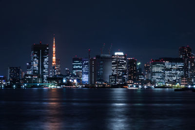 Illuminated city by sea at night
