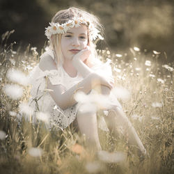 Girl with a melancholy look, sitting in a field with lots of flowers