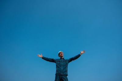 Rear view of woman standing against clear blue sky