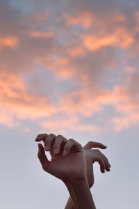 Person holding umbrella against sky during sunset