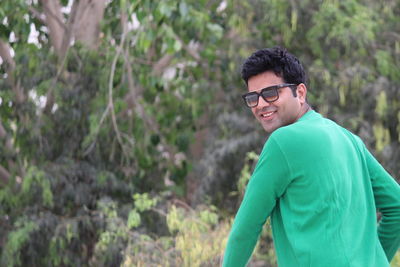 Portrait of man wearing sunglasses against trees