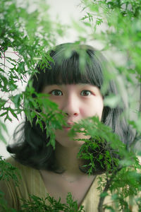 Close-up portrait of beautiful woman by plants
