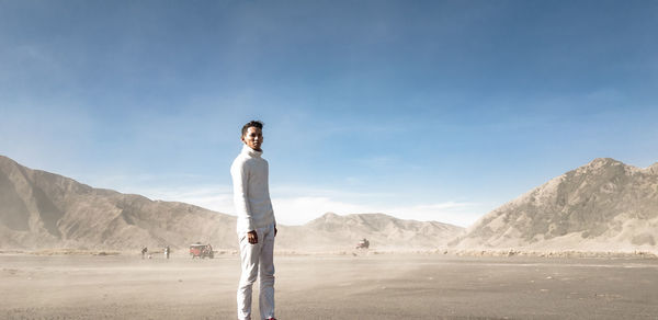 Portrait of man standing at desert against mountain 