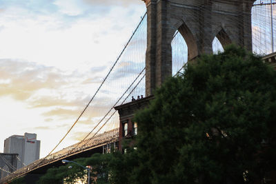 Low angle view of suspension bridge against cloudy sky