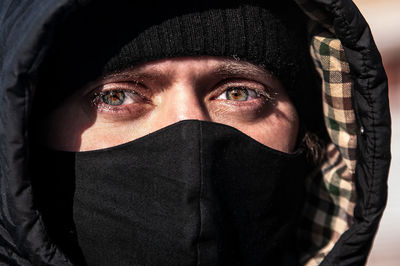 Close-up portrait of a man wearing hat and mask . eye on the camera