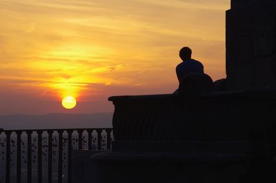 Silhouette man by sea against sky during sunset