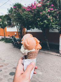 Cropped hand holding ice cream cone outdoors