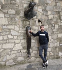 Full length portrait of young man standing against wall