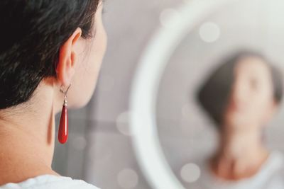 Side view of young woman looking through window