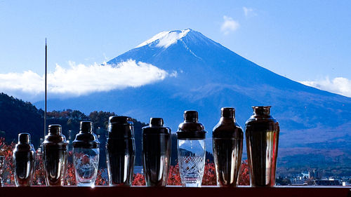 Panoramic view of bottles and mountains against blue sky