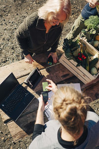 High angle view of farmer receiving payment from female customer at market