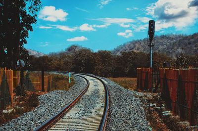 Empty railroad tracks by trees against sky