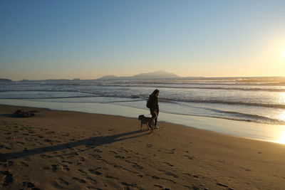 Full length of man on beach against sky during sunset