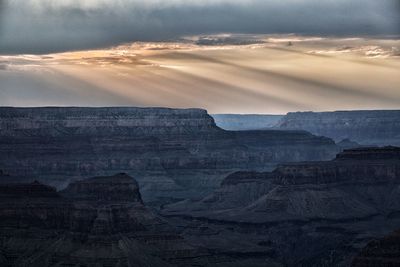 Rocky mountains at grand canyon against cloudy sky during sunset