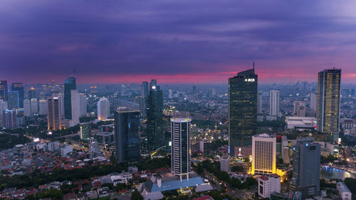 Illuminated cityscape against sky during sunset