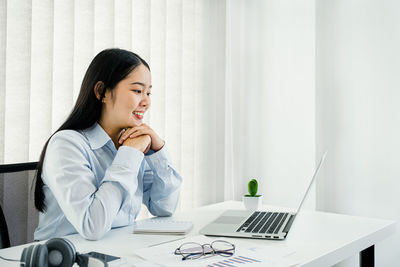 Young woman using phone while sitting on table