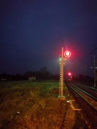 Illuminated railroad tracks against sky at night