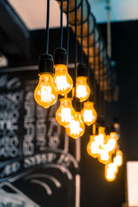 Low angle view of illuminated light bulbs hanging from ceiling