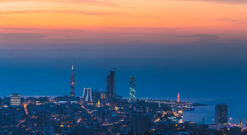 Illuminated cityscape against sky during sunset