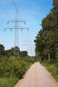 Transmission line or overhead power cable with electricity pylons along rural dirt track 