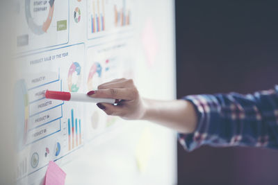 Cropped hand of woman explaining chart in office