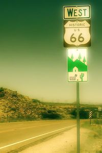 Close-up of road sign by sea against sky