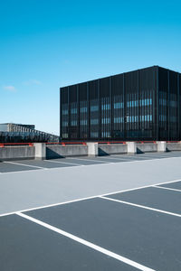 View of modern building from car park against blue sky