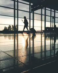 Silhouette woman standing at airport against sky during sunset
