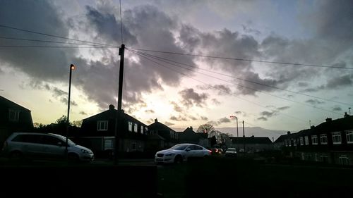 Cars on road against cloudy sky