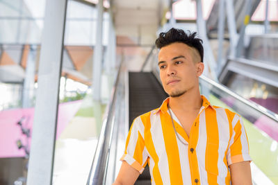 Portrait of young man standing against window