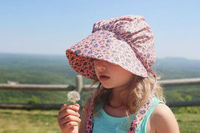 Close-up of girl holding umbrella against clear sky