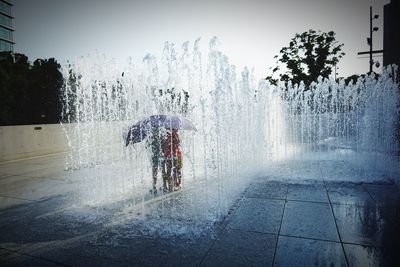 Water splashing on fountain in city against sky