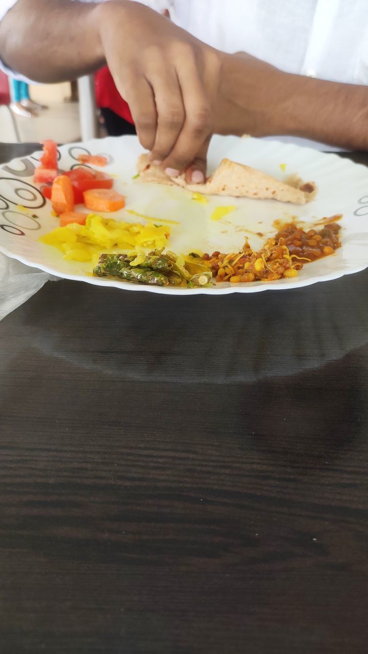 MIDSECTION OF PERSON HAVING FOOD ON TABLE