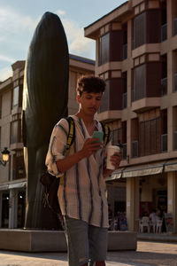 A young man with afro hair walks at sunset while using his cell phone