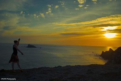 Woman standing on beach against sky during sunset