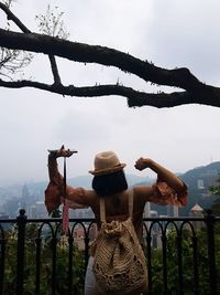 Rear view of woman standing by railing against sky