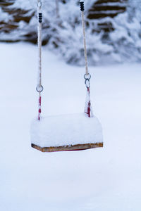 Close-up of swing hanging on snow covered land