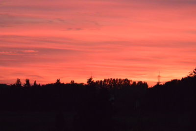Silhouette trees against dramatic sky during sunset