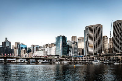 Modern buildings by river against sky in city