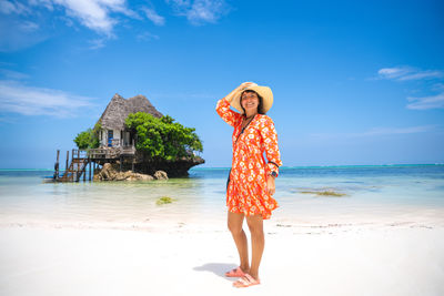 Rear view of woman standing at beach against sky