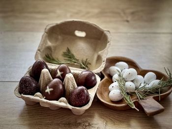 Close-up of chocolate and praline easter eggs in cardboard carton and wooden container on table.