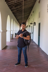 Portrait of a young man with backpack in corridor