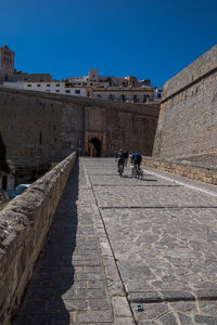 People walking in historic building against sky